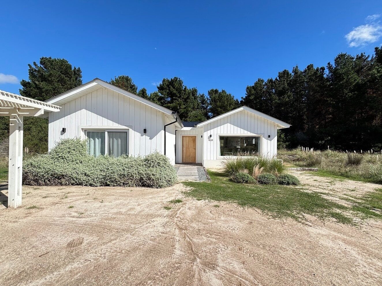 Casa blanca de madera rodeada de pinos en Costa Esmeralda